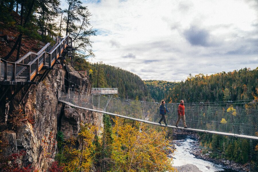 Hikers crossing a suspension bridge in a forest in autumn