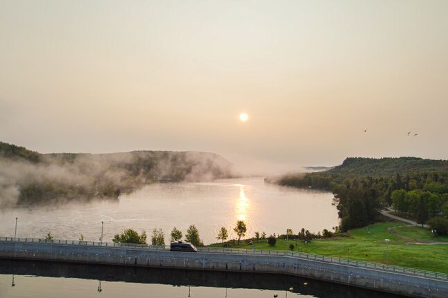 Van driving along the Fjord Route at sunrise with mist