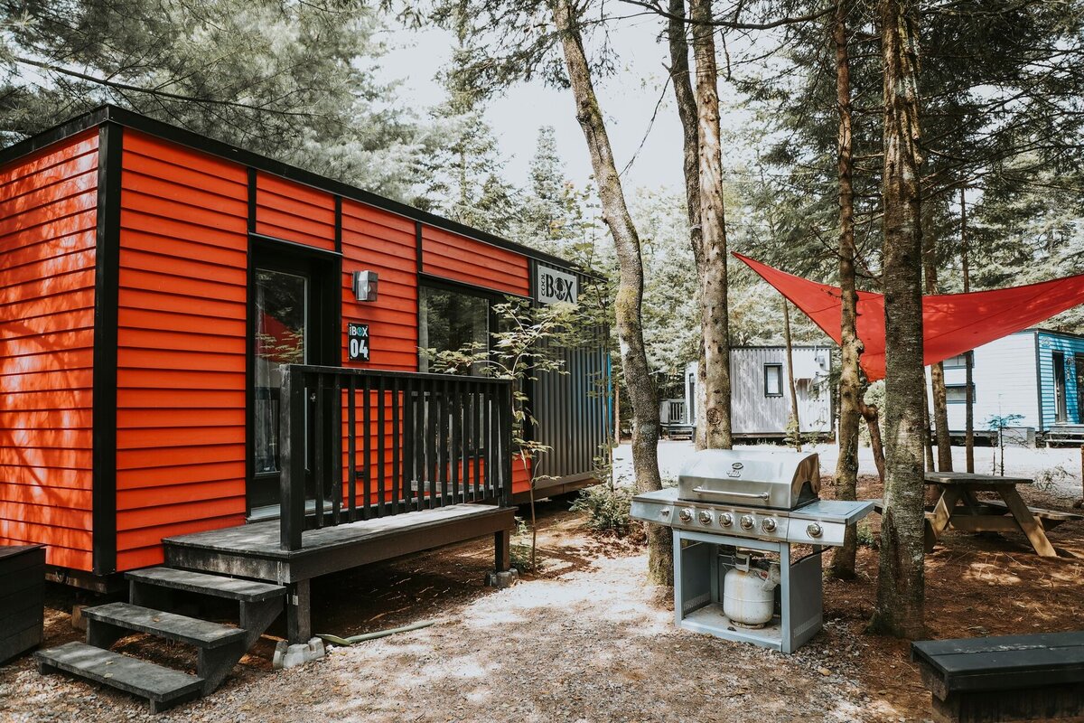 Mini chalet rouge en forêt avec terrasse et barbecue