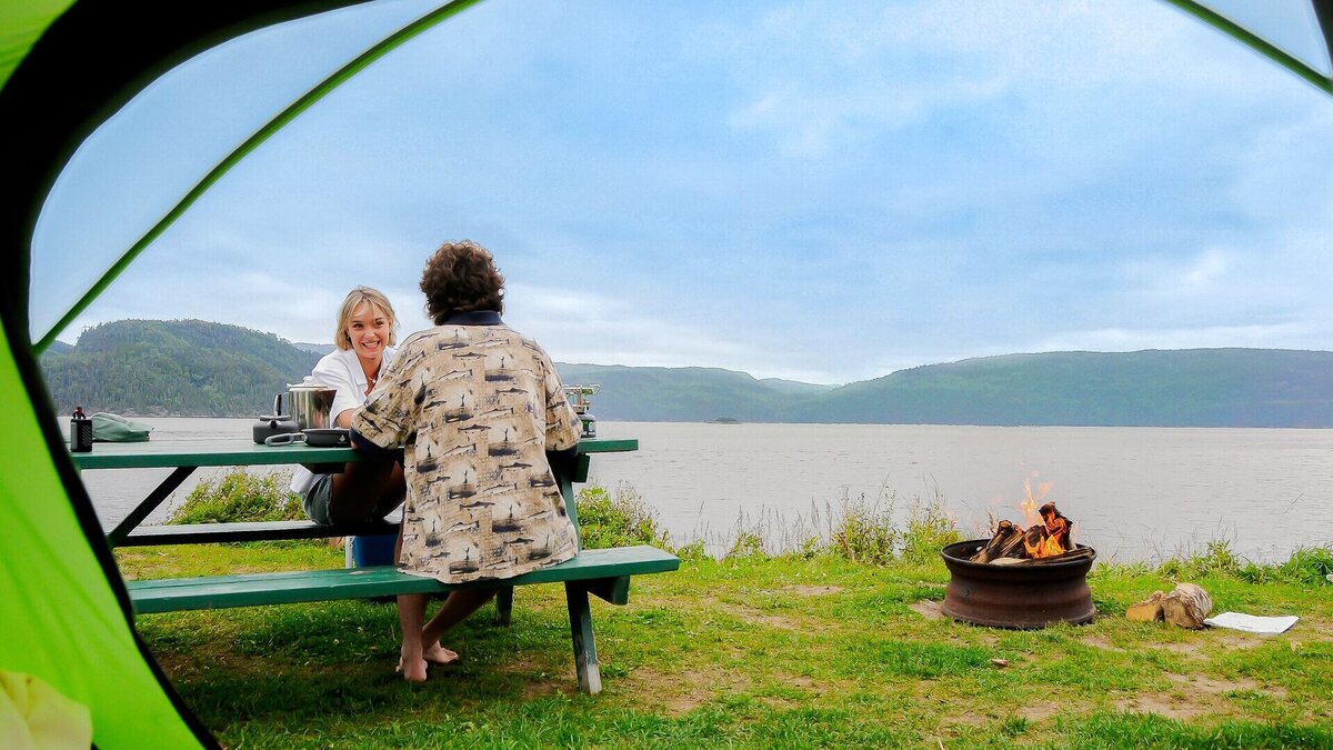 Couple assis à une table de pique-nique devant le Fjord du Saguenay