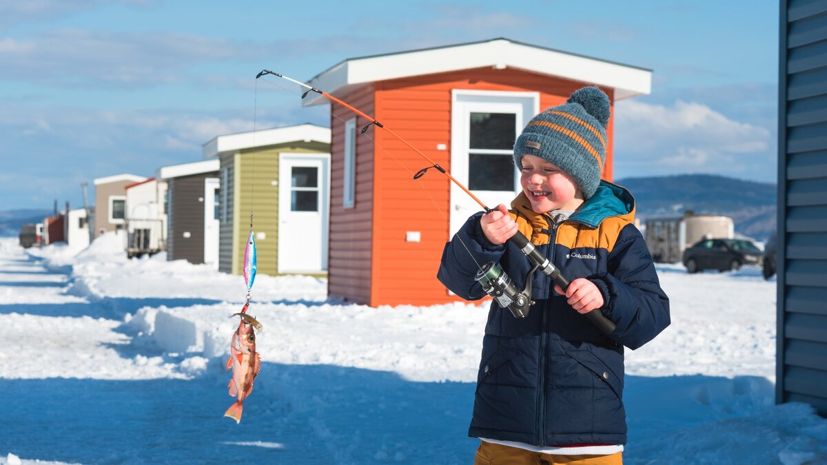 Young fisherman with a redfish at the ice fishing village