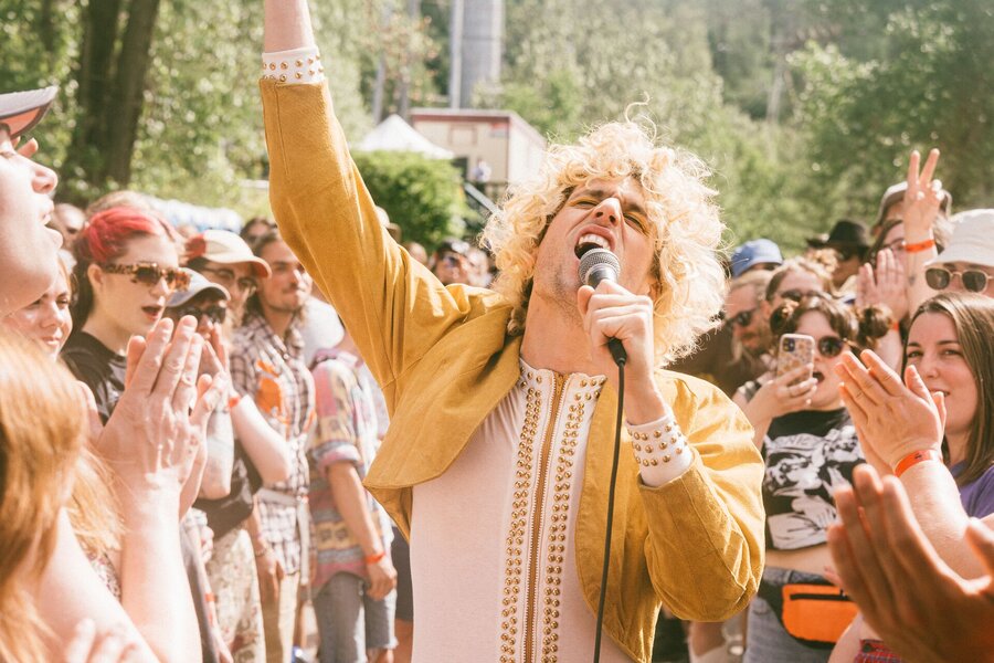 Chanteur au micro entouré d’une foule en plein air