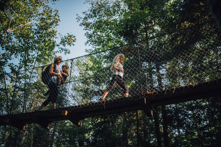 Famille marchant sur une passerelle suspendue en forêt