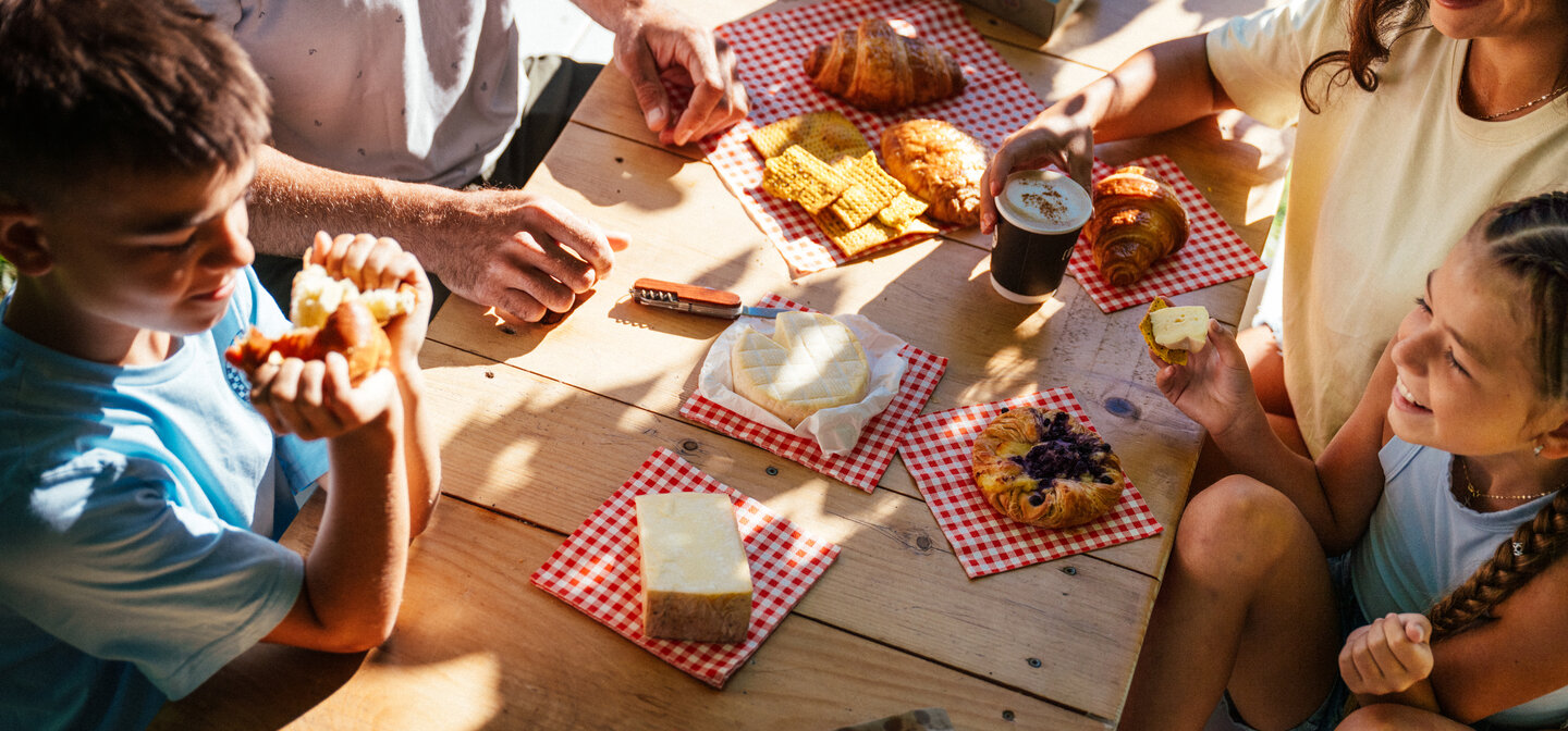 Famille partageant fromages et viennoiseries en terrasse
