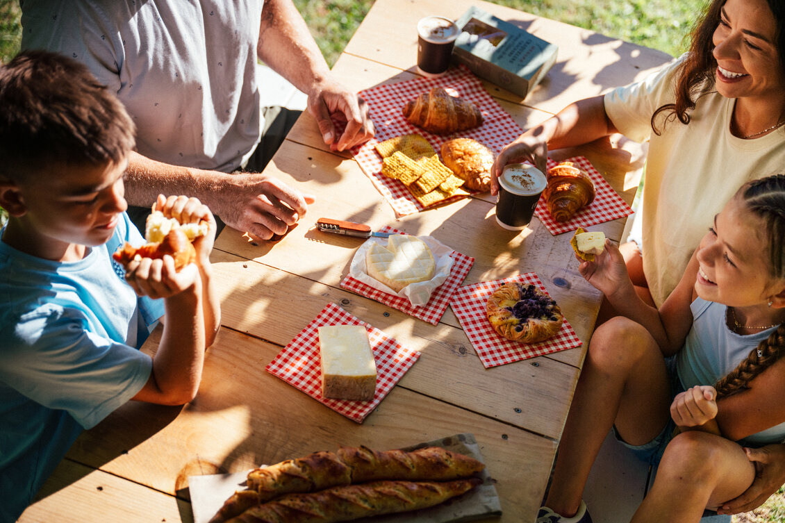 Famille partageant fromages et viennoiseries en terrasse