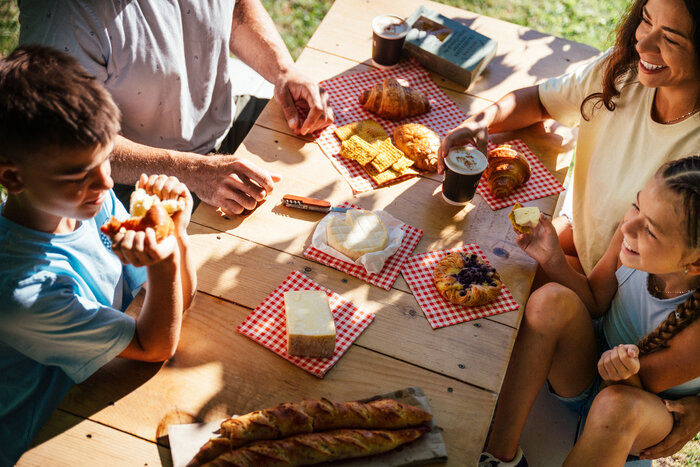 Famille partageant fromages et viennoiseries en terrasse