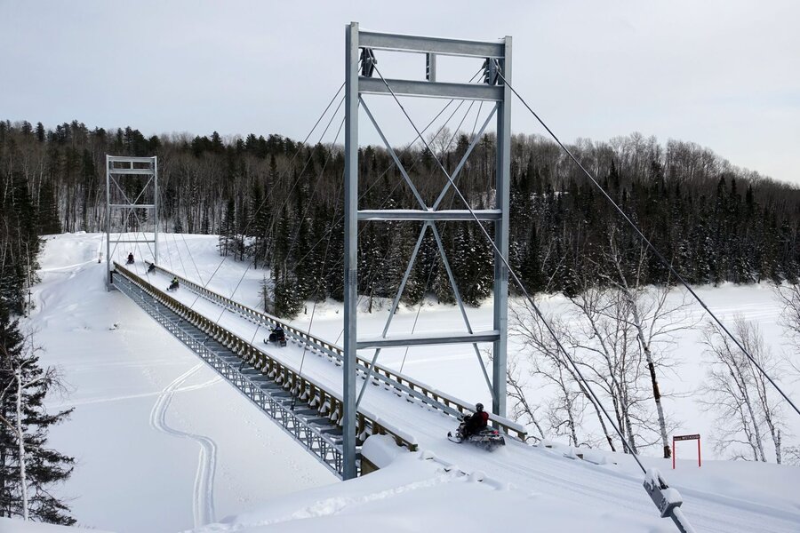 Motoneigistes traversant la passerelle de la rivière Mistassibi en hiver
