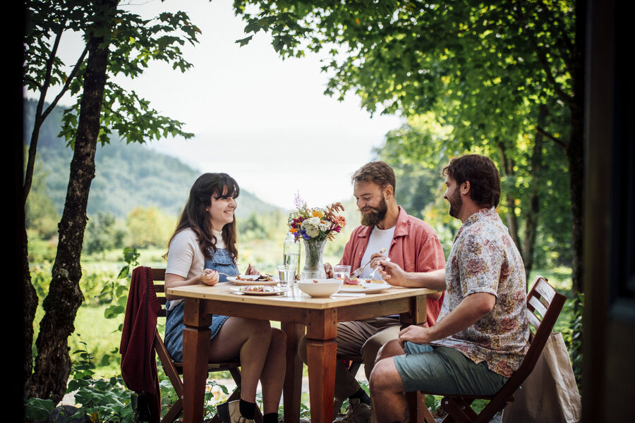 Trois personnes mangeant à une table en pleine nature
