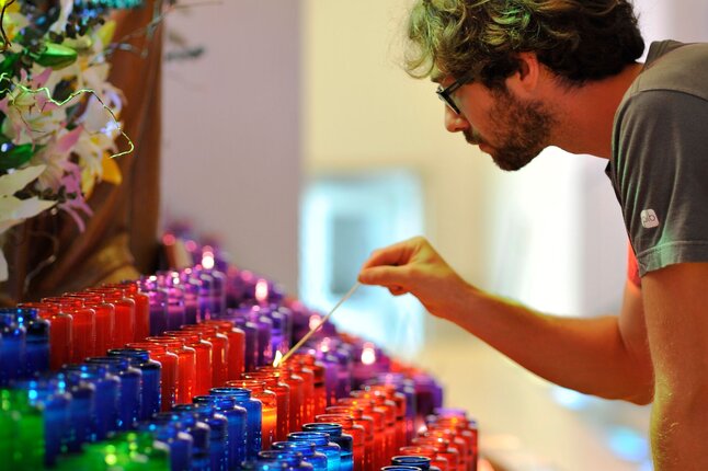Person lighting colorful candles in Ermitage Saint-Antoine