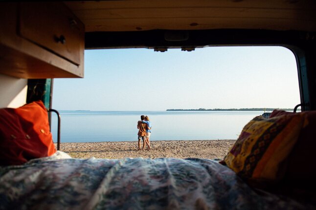 Couple sharing coffee from van by Lac Saint‑Jean