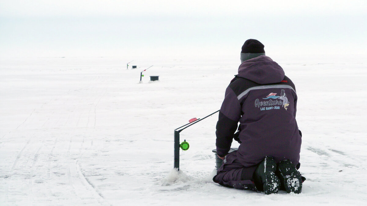 Ice fisherman in front of a fishing hole