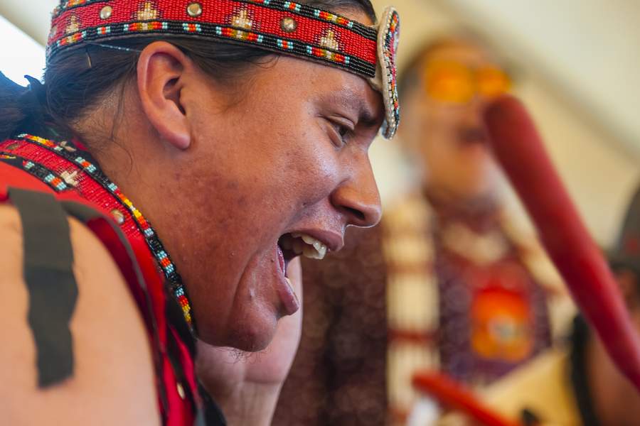 Person in traditional dress singing at the Grand Gathering of First Nations