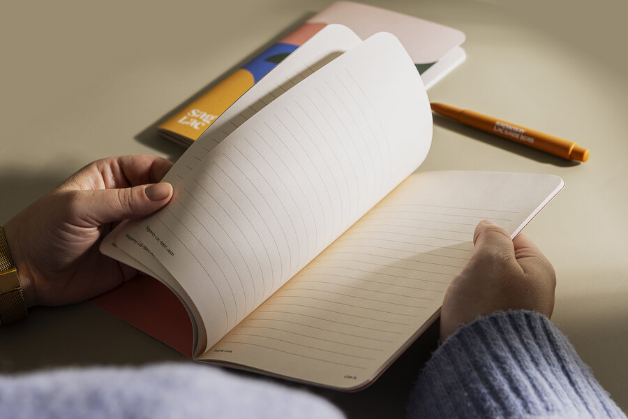 Mains feuilletant un carnet ligné avec crayon orange