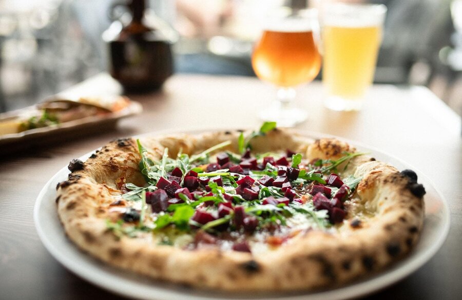 Pizza garnie de betteraves servie avec des bières artisanales