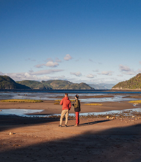 Campeurs prenant un marche avec un café en bordure du fjord du Saguenay